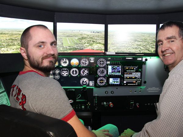 Student and teacher posing in a flight simulator
