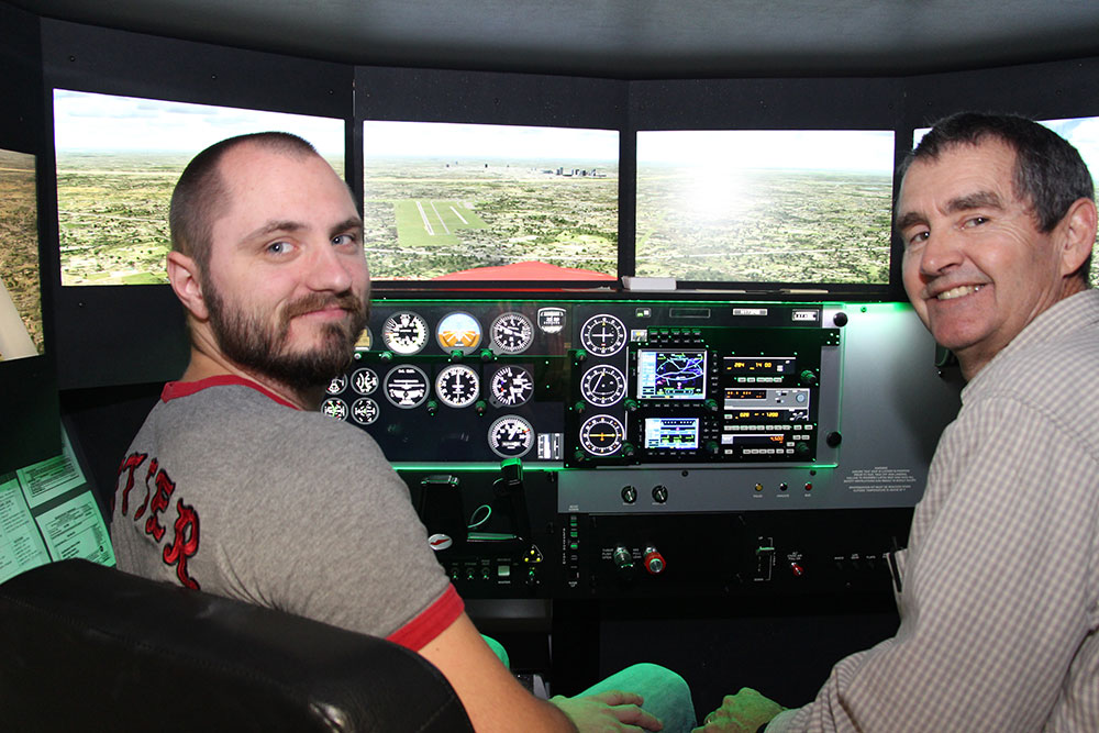 Student and teacher posing in a flight simulator