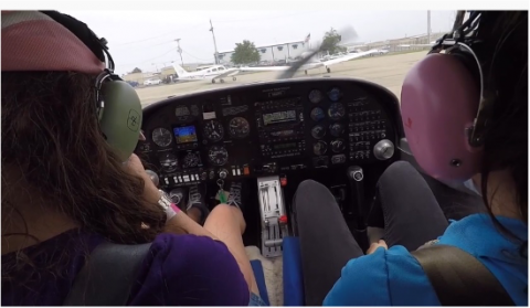 Two people sitting in the cockpit of a plane