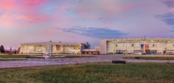 A panoramic photo of hangers and planes at the St. Louis Downtown Airport with the St. Louis skyline in the background.