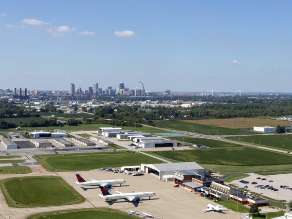 Aerial shot of St. Louis Downtown Airport with planes visible on the ground and the downtown St. Louis skyline in the background