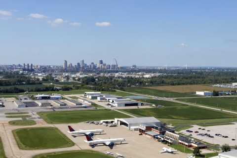 Aerial shot of St. Louis Downtown Airport with planes visible on the ground and the downtown St. Louis skyline in the background