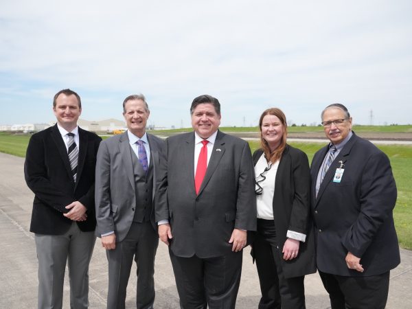 The Governor of Illinois, CEO of Bi-State Development, and others pose on an airport runway.