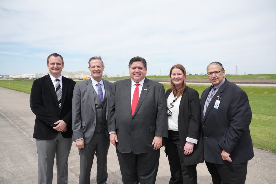 The Governor of Illinois, CEO of Bi-State Development, and others pose on an airport runway.