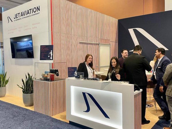 People stand at a Jet Aviation booth at a conference.