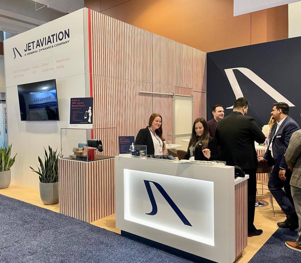 People stand at a Jet Aviation booth at a conference.