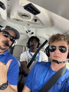 Photo of Jake Yurko and Chris Fuller of SLU with Camper Caleb Carter on board a small plane