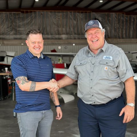 Josiah Bridges and Paul Voorhees of Big River Aviation shake hands inside a hangar