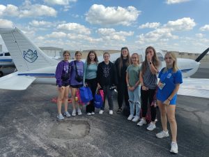 Photo of female high school students in front of a plane