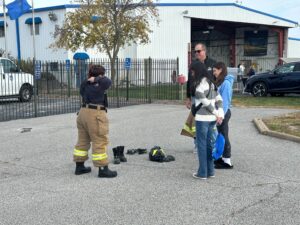 Two young women with a female airport firefighter