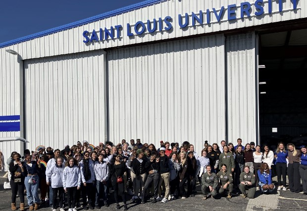 Group shot of Girls in Aviation participants, instructors, and staff outside the Saint Louis University hangar